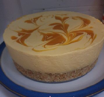 A cheesecake on a biscuit base with a mango puree swirled across the top
