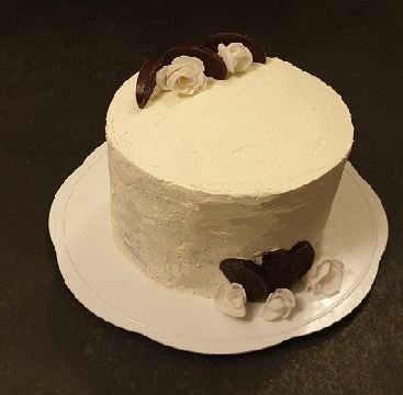 A plain buttercream cake finished with chocolate curls and white sugar roses