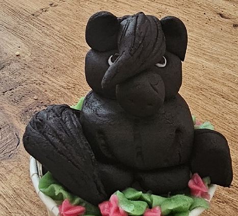 A cake modelled as a black horse sitting on green sugar leaves