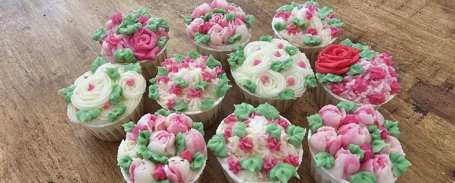 Cup cakes piped with buttercream roses and peonies in pink, white and green