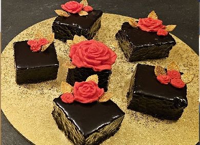 Chocolate-glazed slices topped with red sugar roses on a gold board
